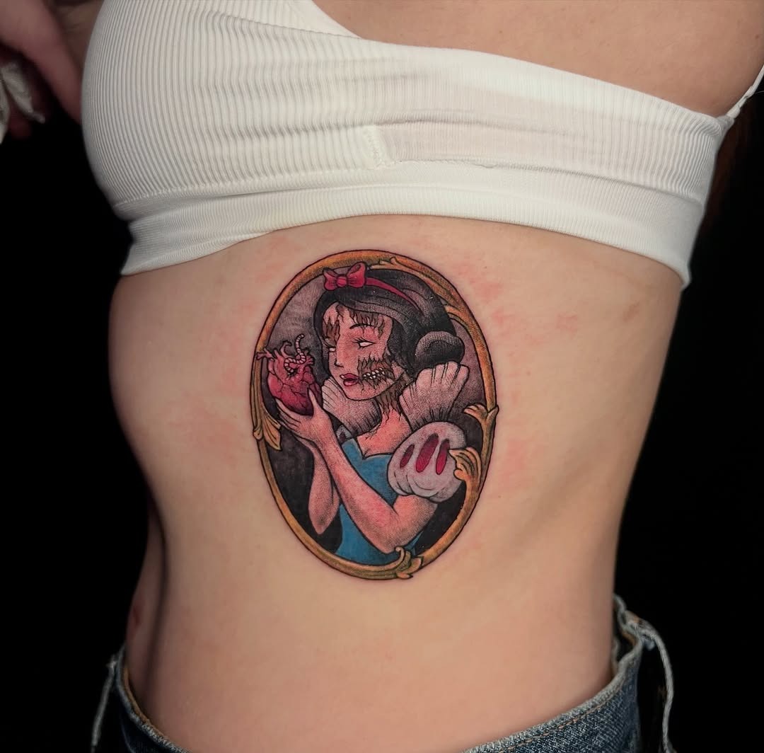 This captivating tattoo features Snow White holding a heart, surrounded by a vintage-style frame.