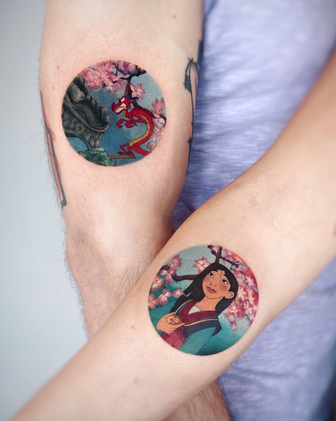 This tattoo features Mulan surrounded by cherry blossoms, symbolizing beauty and courage.