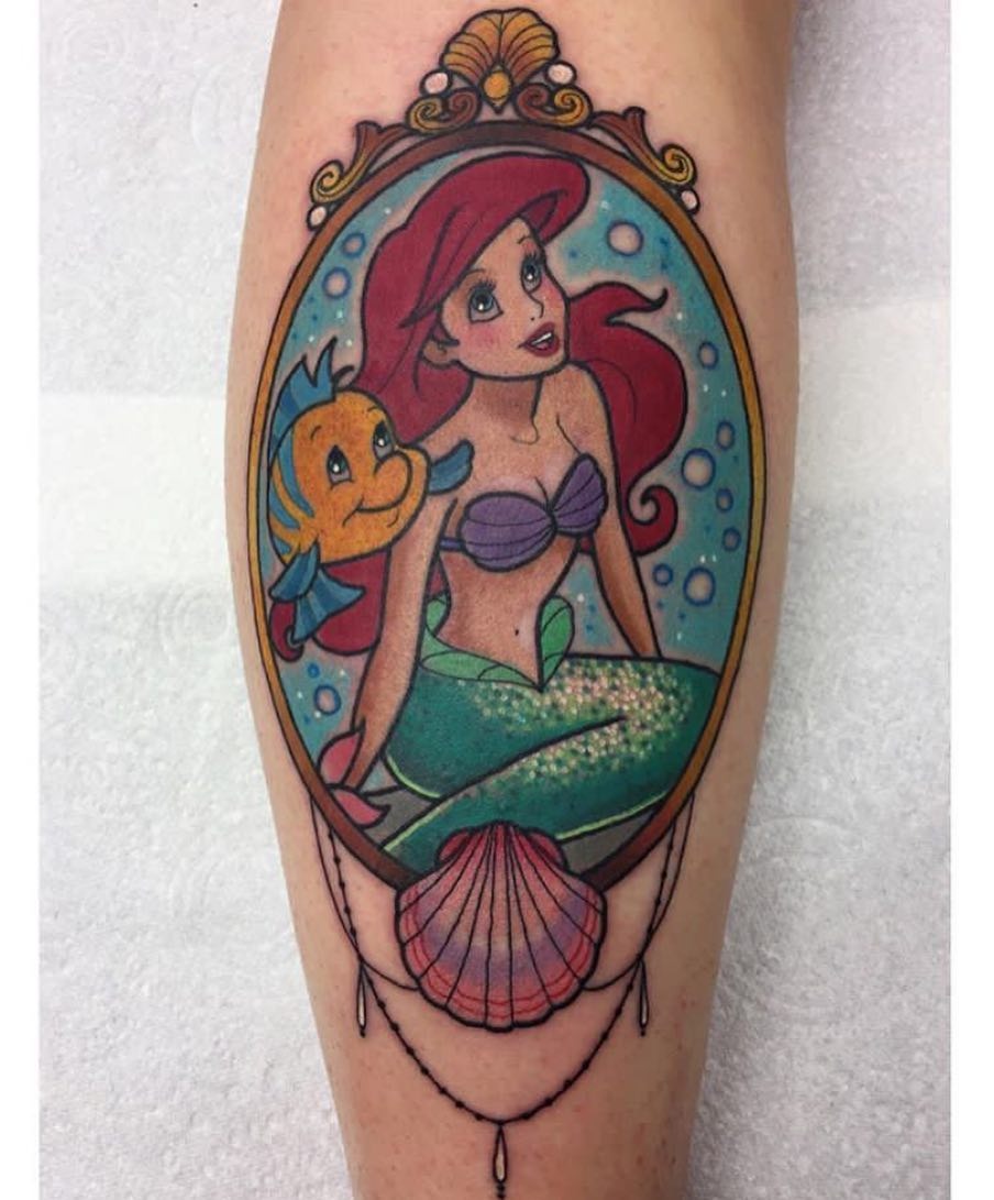 This enchanting tattoo features Ariel with her red hair and Flounder, capturing the whimsical essence of the sea.