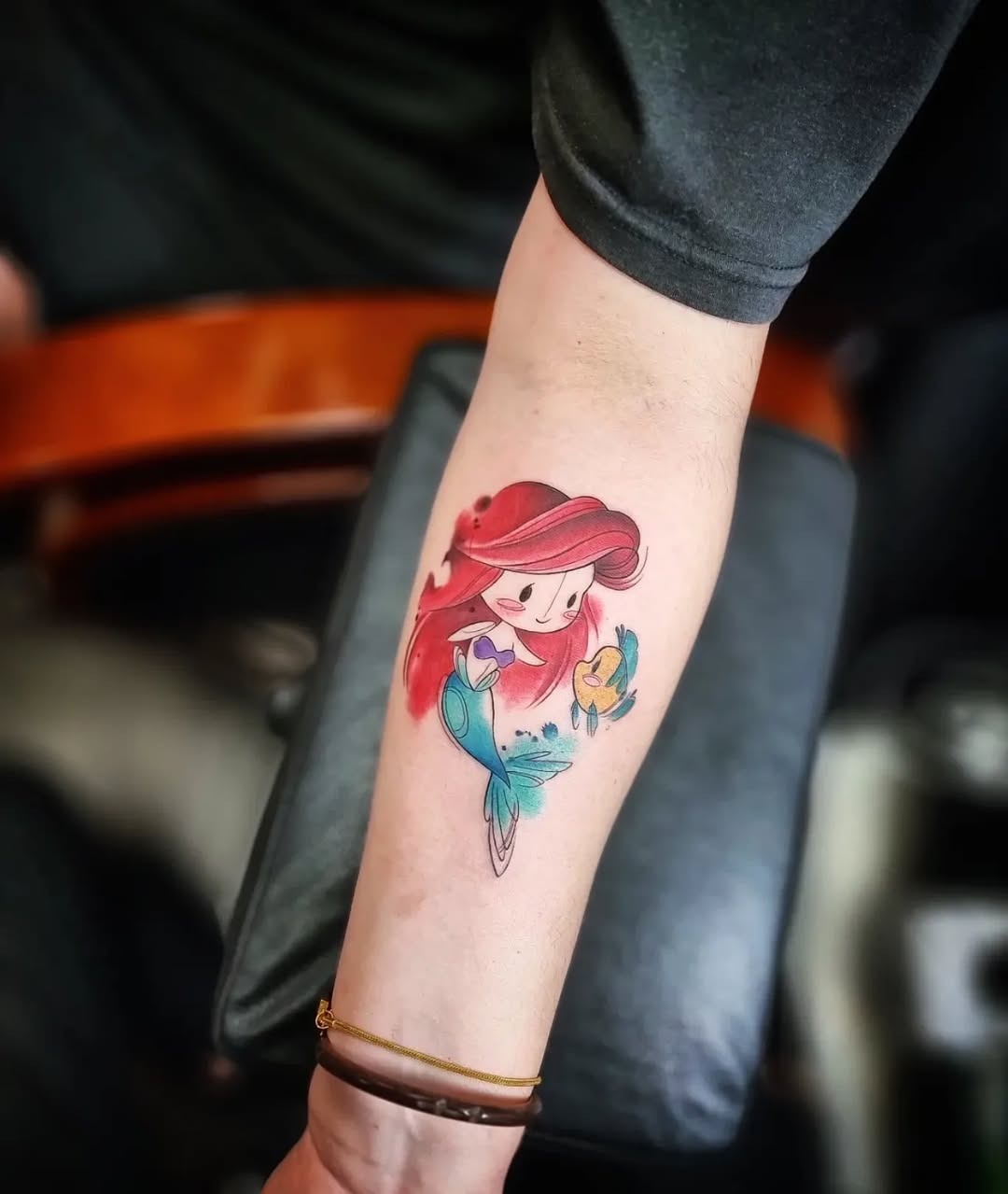 This whimsical tattoo features Ariel, the beloved Disney princess, adorned with her iconic flowing red hair.