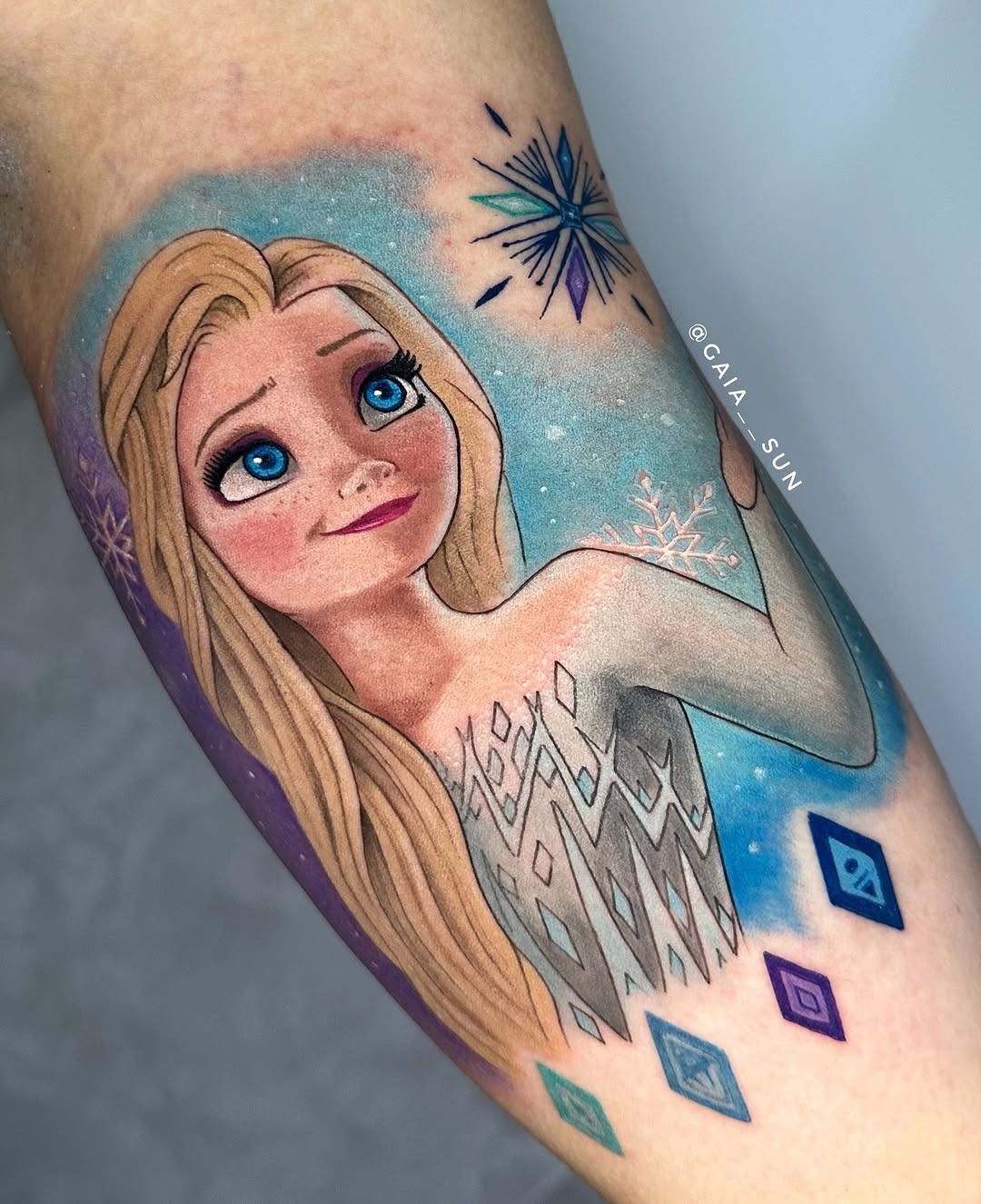 This tattoo features Elsa, highlighting her enchanting blue eyes and flowing blonde hair.