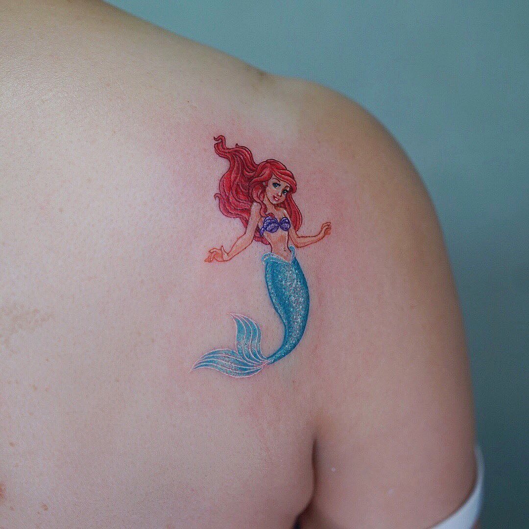 This tattoo captures the enchanting essence of Ariel, featuring her iconic red hair and shimmering tail.