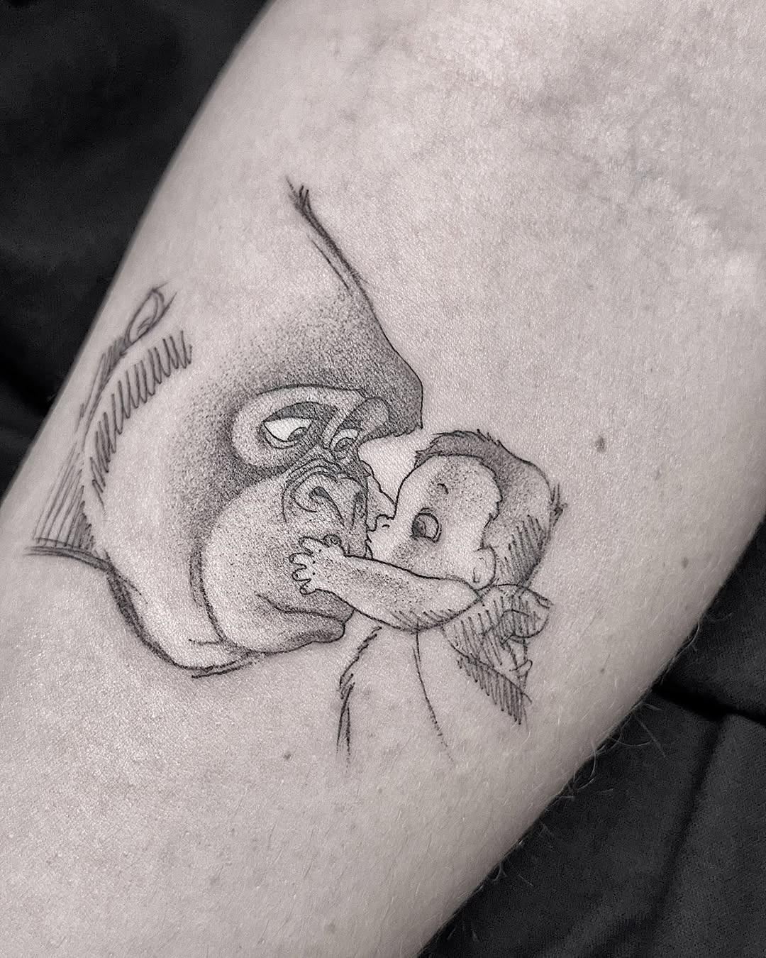 This charming tattoo features a baby interacting with Mickey Mouse, capturing a sweet moment.