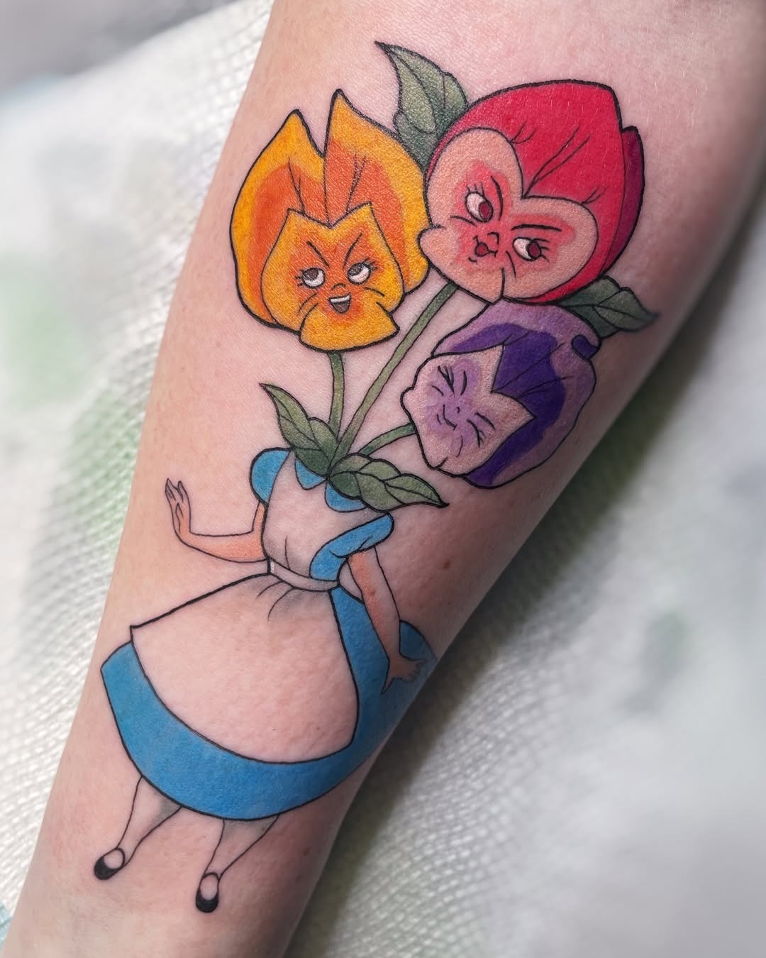 This delightful tattoo features Alice with whimsical flowers.