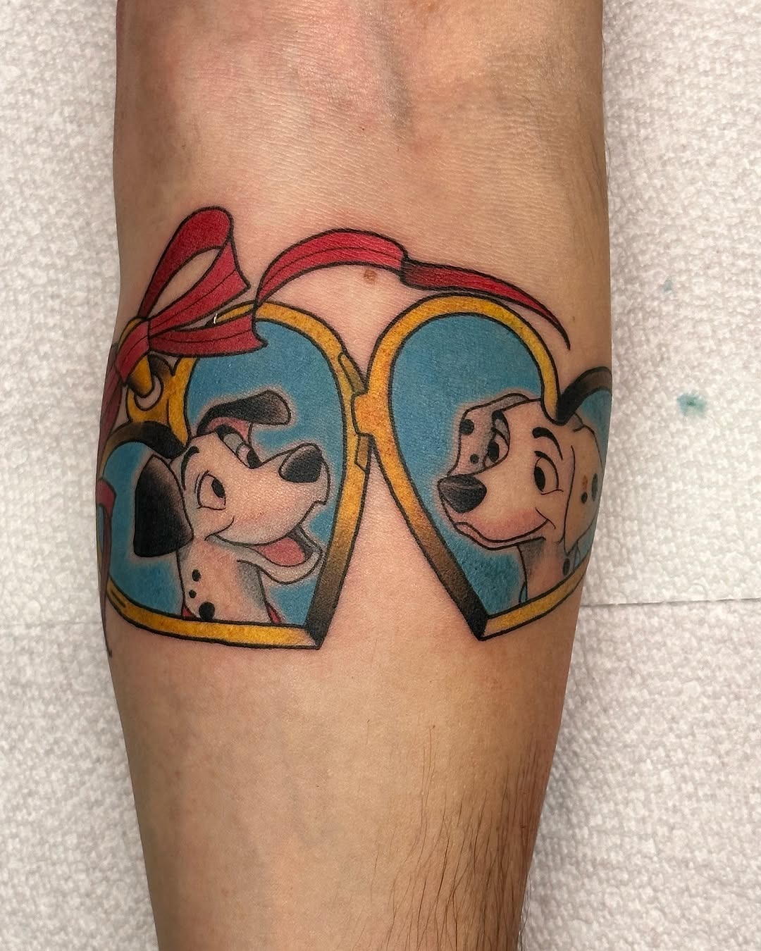 This tattoo features two joyful Dalmatians framed in colorful hearts.