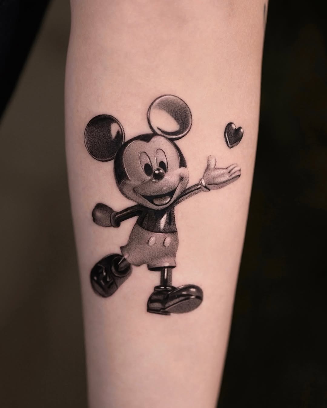 This tattoo features the classic Mickey Mouse in black and grey.