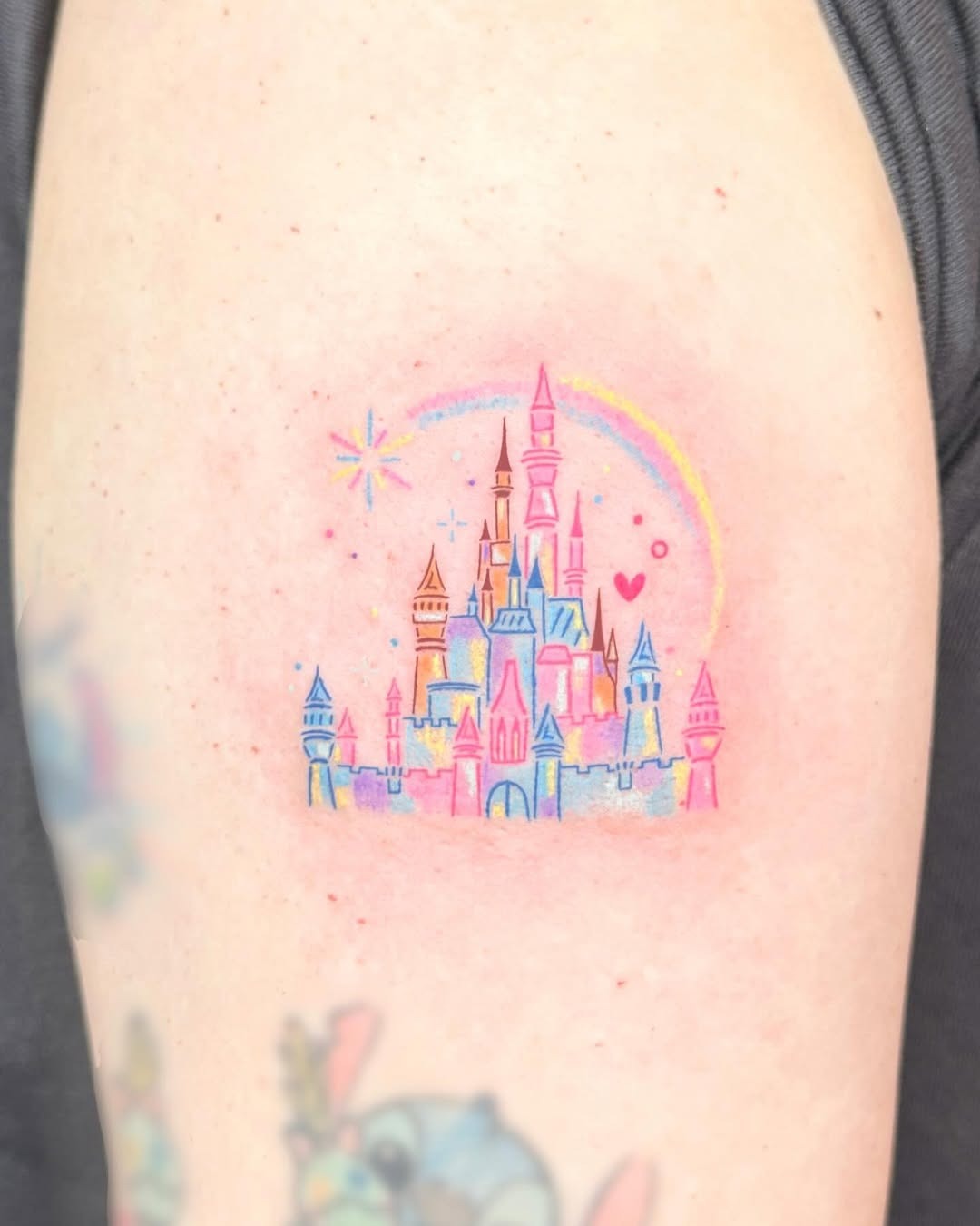 This tattoo features a dreamy pastel Disney castle with delicate details that evoke nostalgia.