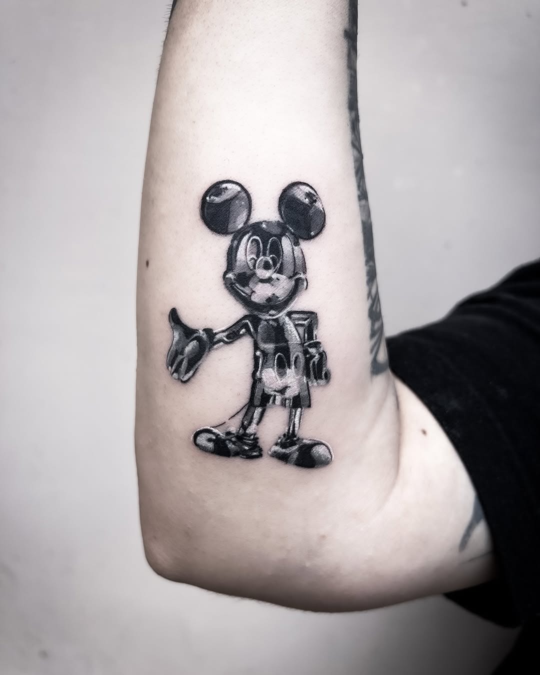 This tattoo features a striking black and gray depiction of Mickey Mouse, exuding a timeless charm.