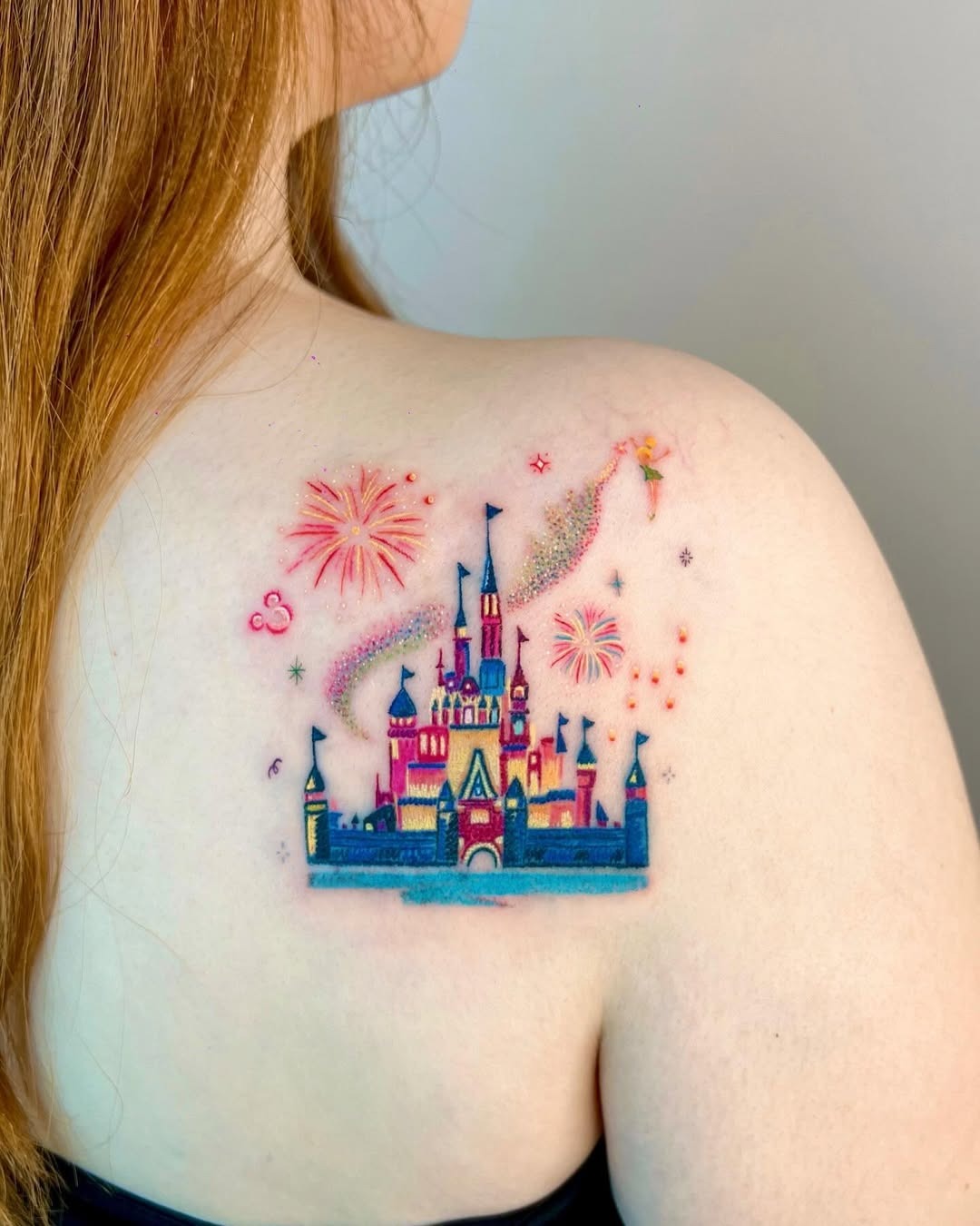 This tattoo features the iconic Disney castle accompanied by whimsical fireworks and fairy dust.