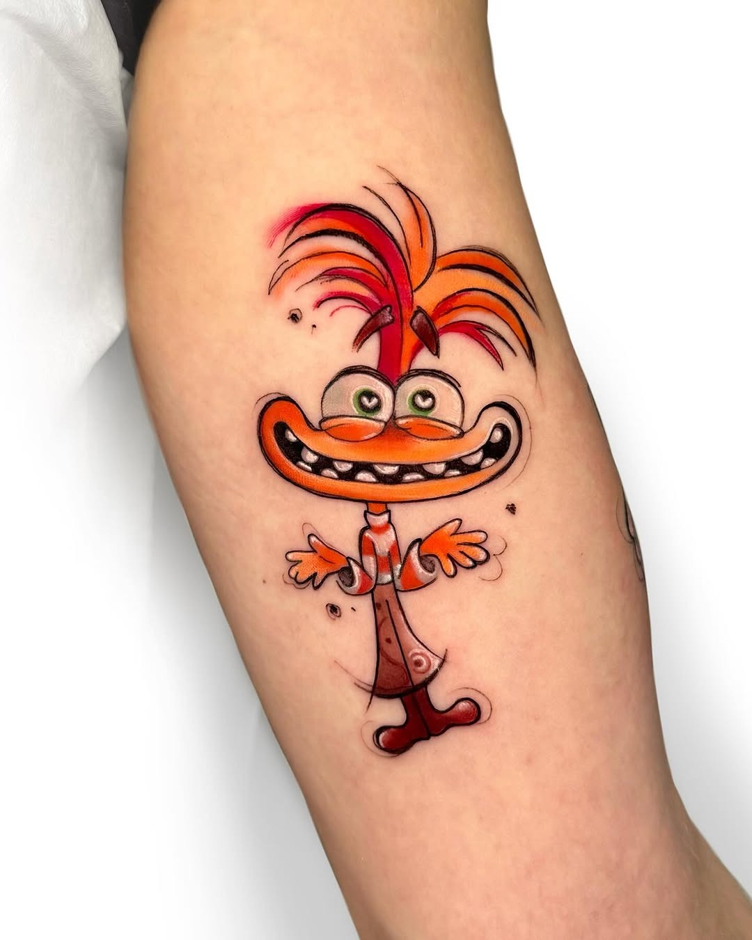 This tattoo features a quirky Disney character with bright orange hair and a big smile.