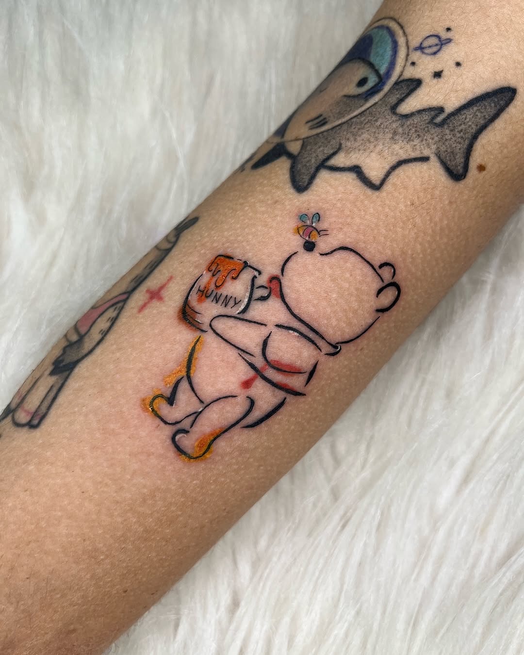 This adorable tattoo features Winnie the Pooh joyfully holding a pot of honey.