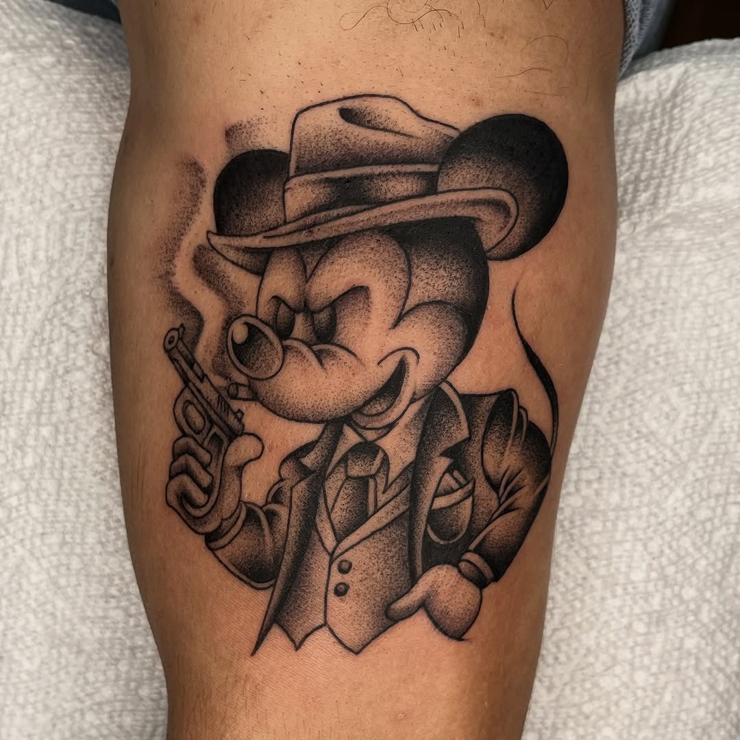 This tattoo showcases a unique take on Mickey Mouse, depicting him as a suave gangster.