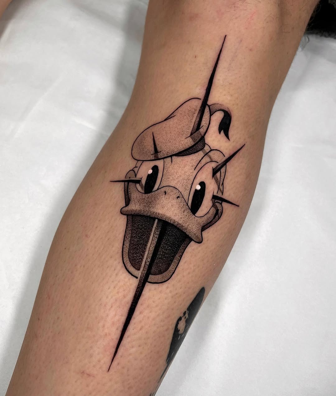This tattoo features a cartoonish Donald Duck with a dynamic burst effect.