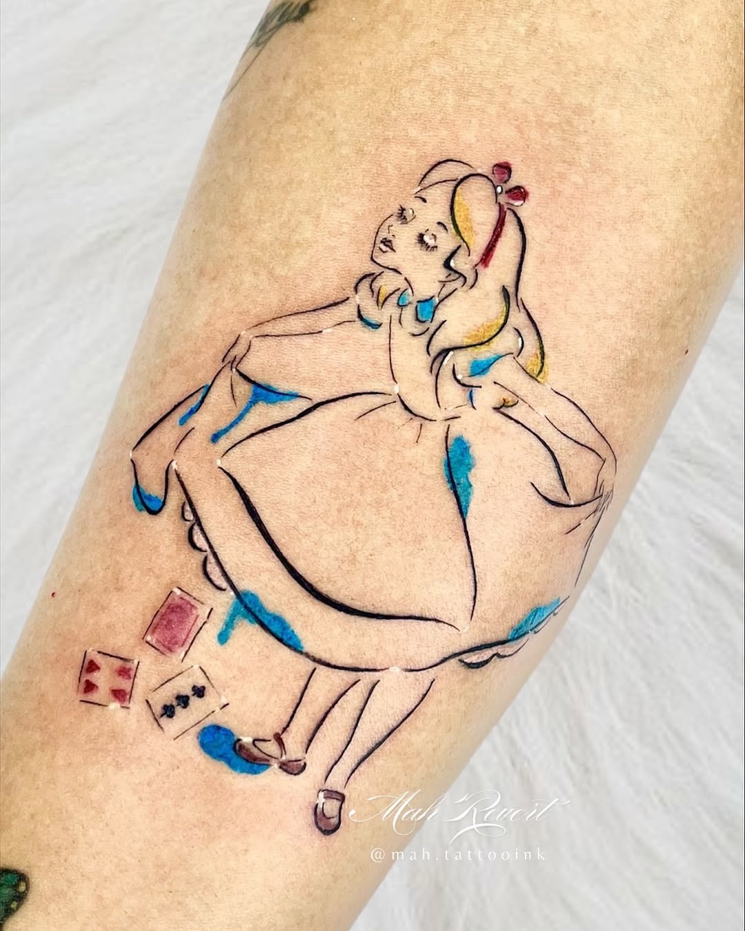 This tattoo features Alice from Wonderland, capturing her curious spirit.