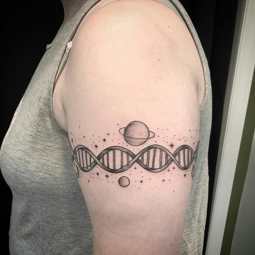 This tattoo features an intricate DNA strand design adorned with planets and stars.