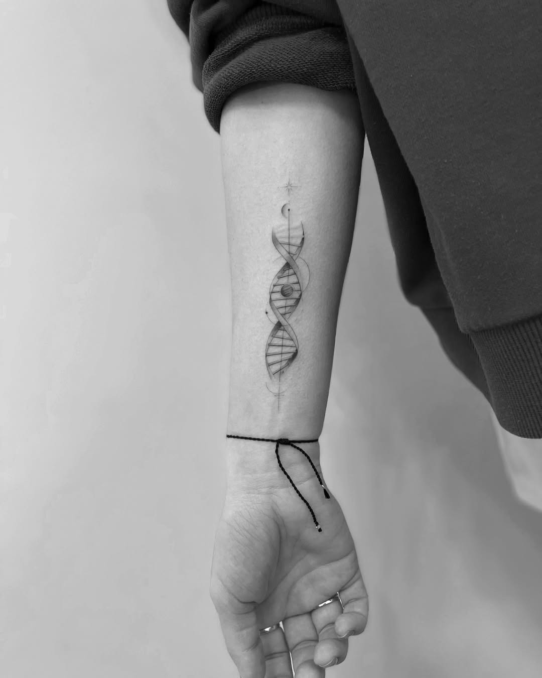This tattoo showcases a mesmerizing DNA double helix, intricately designed in black and white.