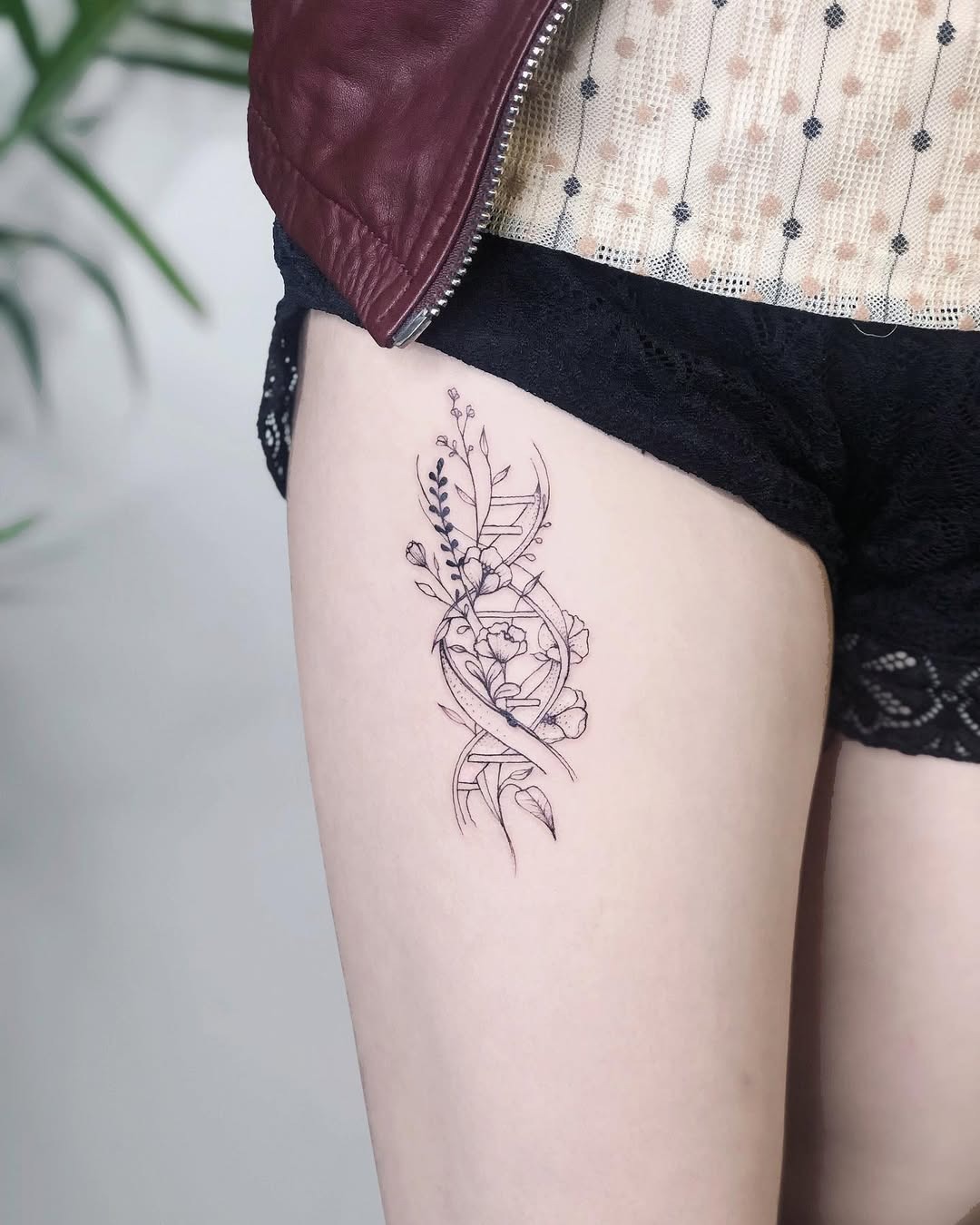 This tattoo features an intricate design combining floral elements and a DNA strand, showing the connection between nature and science.