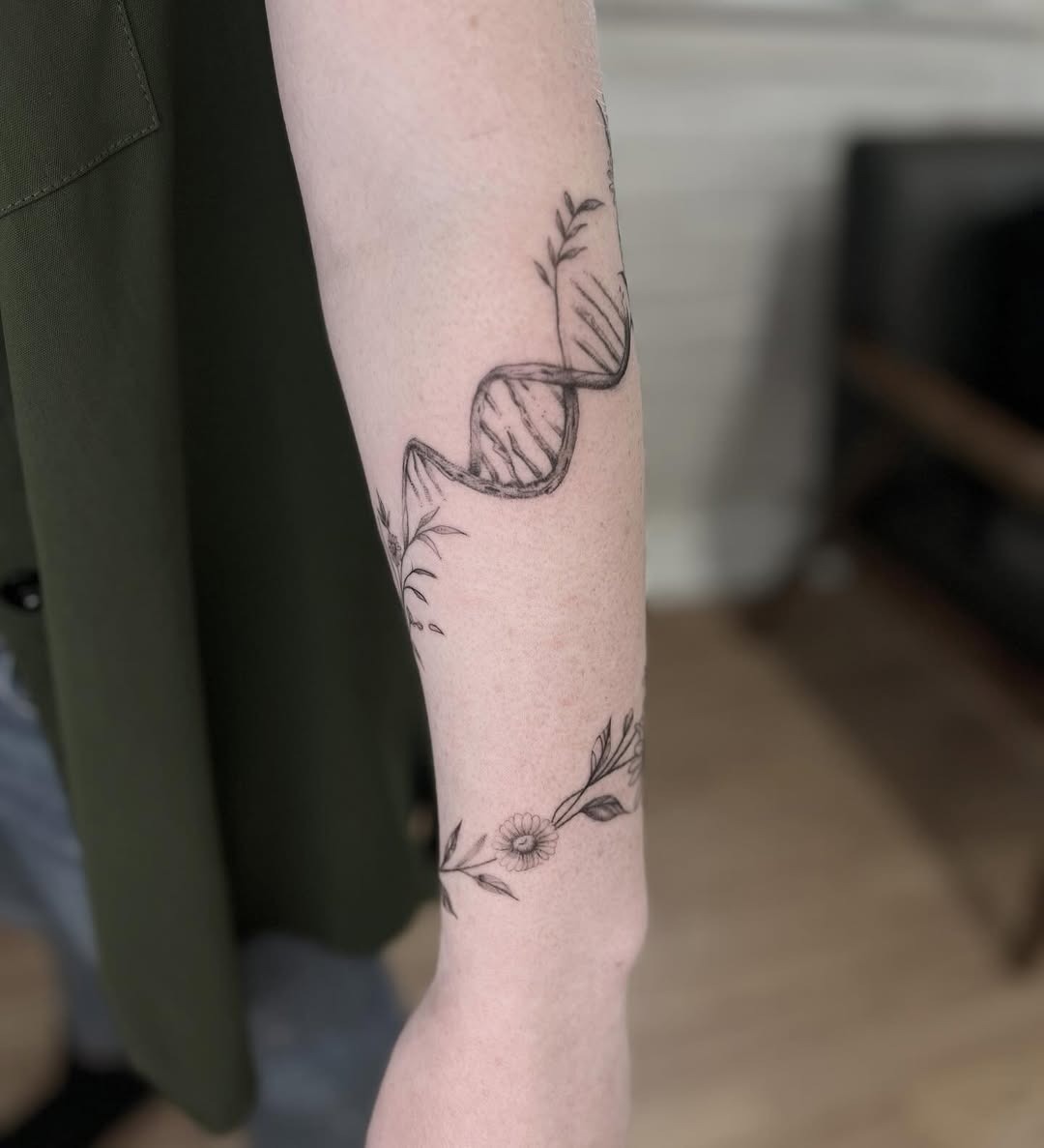 This tattoo features an elegant DNA strand intertwined with delicate floral elements.