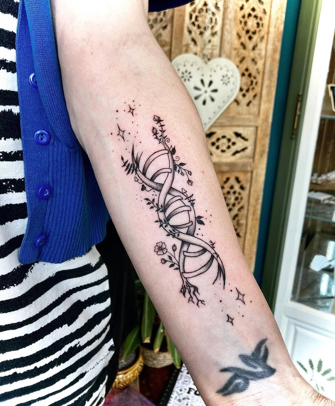 This stunning tattoo showcases a DNA double helix entwined with delicate floral elements.