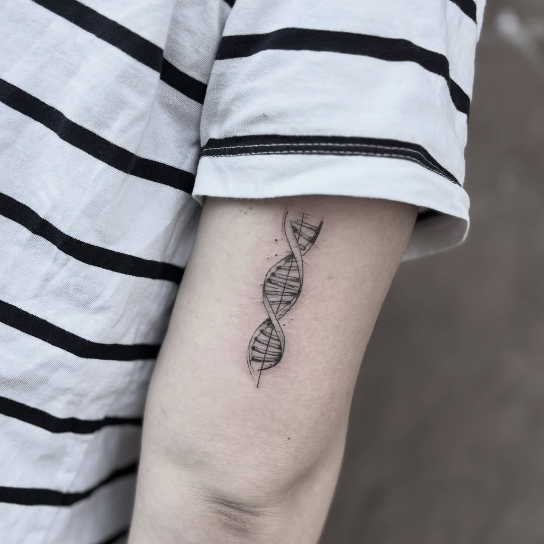 This tattoo features a sleek DNA double helix elegantly inked on the forearm.