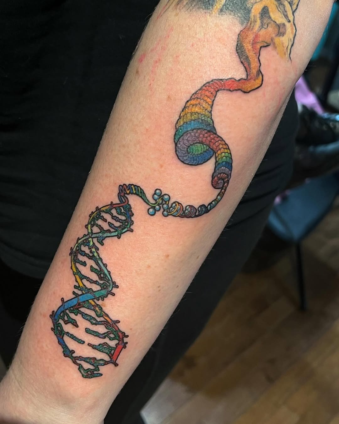 This stunning DNA tattoo showcases a rainbow spiral intertwined with the classic double helix.