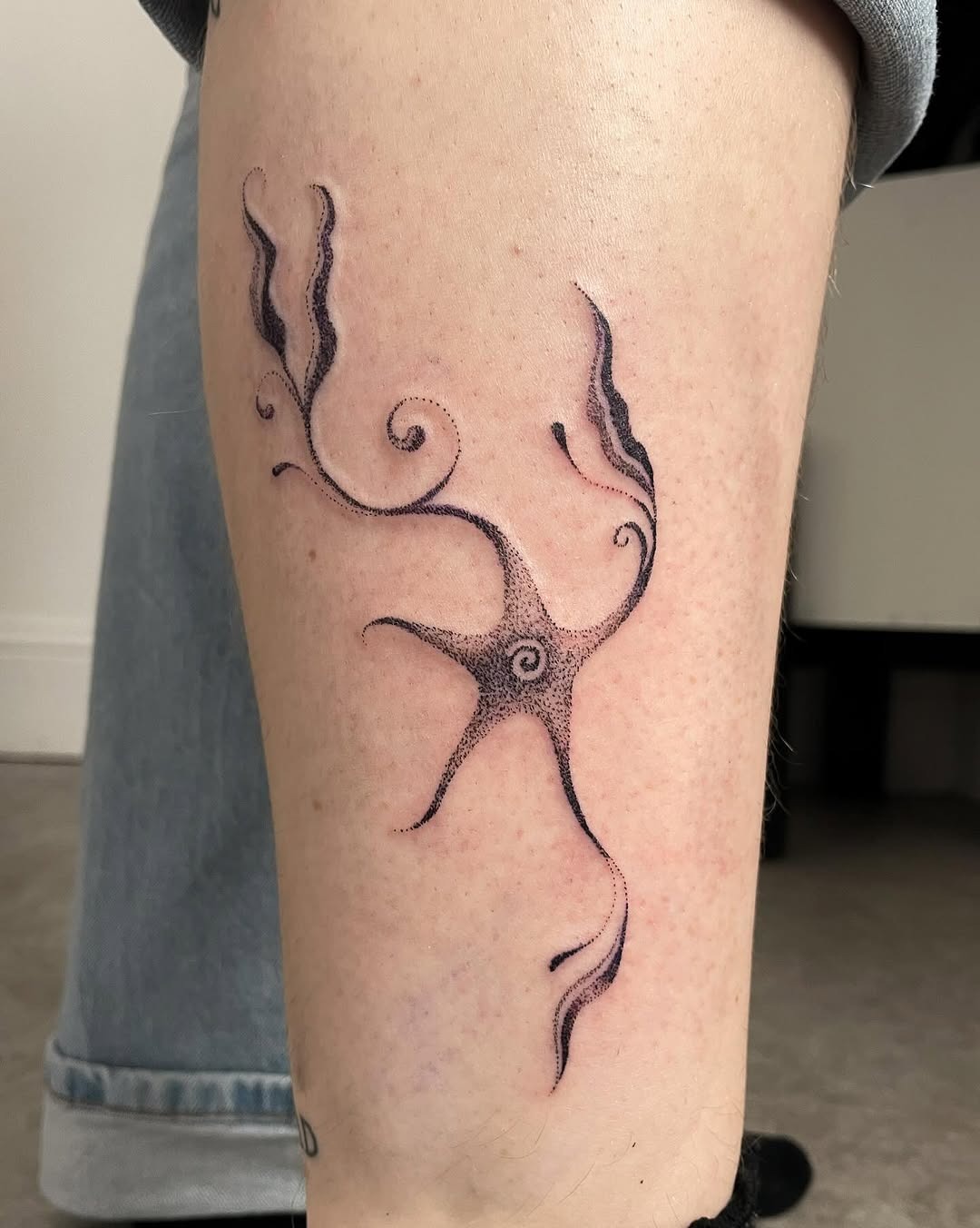 This dotwork tattoo showcases an abstract design, featuring intricate swirling lines and dot patterns.