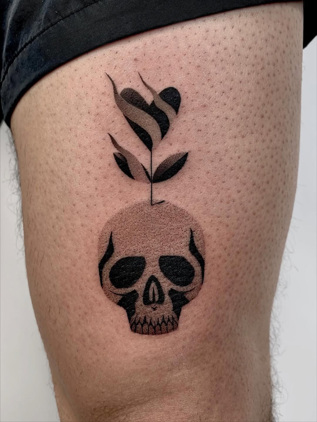 This tattoo features a striking dotwork skull adorned with a delicate plant growing from it.