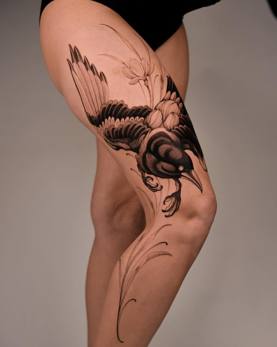 This stunning tattoo features a beautifully detailed bird in dotwork style, perched gracefully among flowing floral elements.