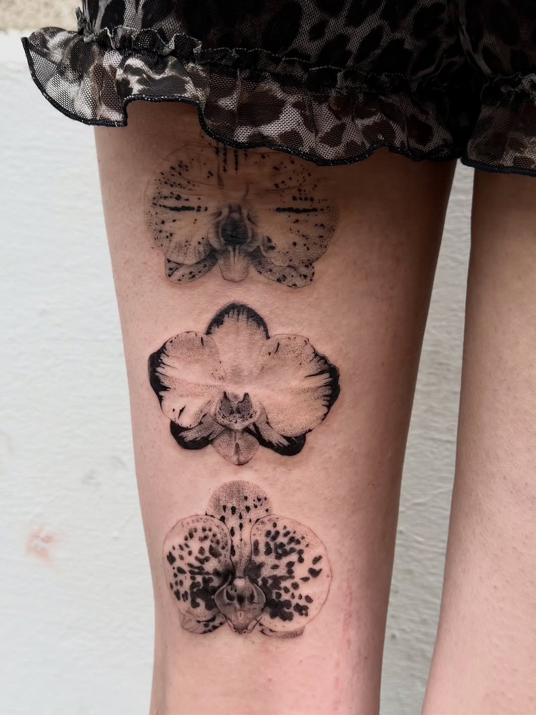 This tattoo showcases three stunning orchids, each delicately designed using dotwork techniques.