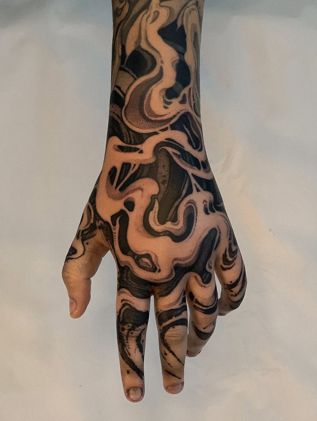 This hand features a captivating dotwork tattoo design, showing intricate swirling patterns that flow seamlessly across the skin.