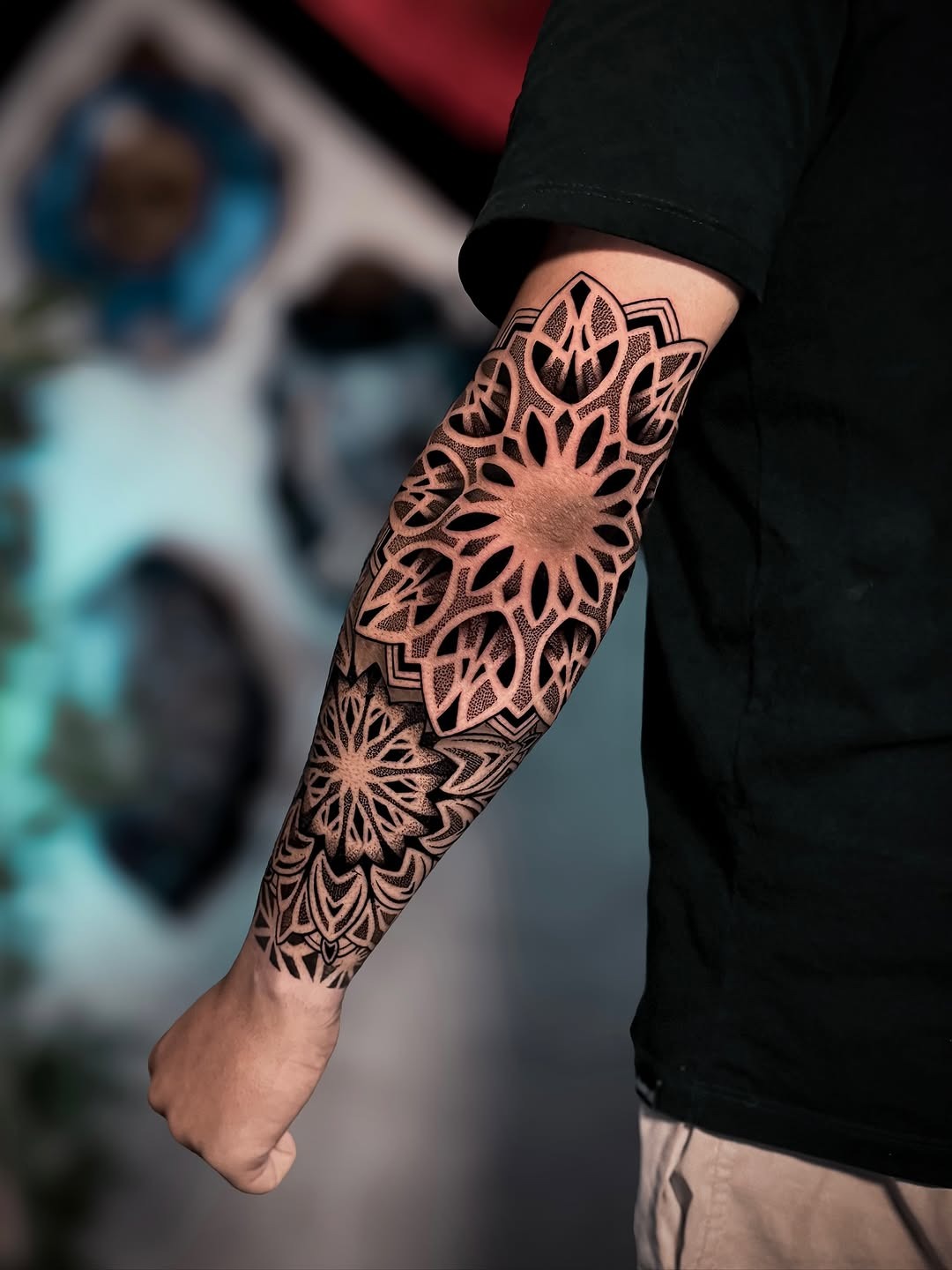 This stunning forearm tattoo showcases an intricate dotwork flower design that beautifully blends geometric patterns with organic shapes.