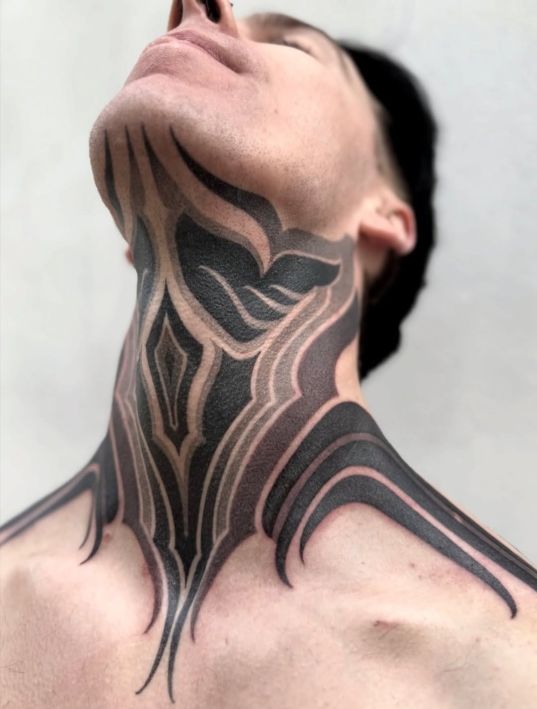 This bold neck tattoo showcases an intricate dotwork pattern that flows gracefully around the neck and shoulders.