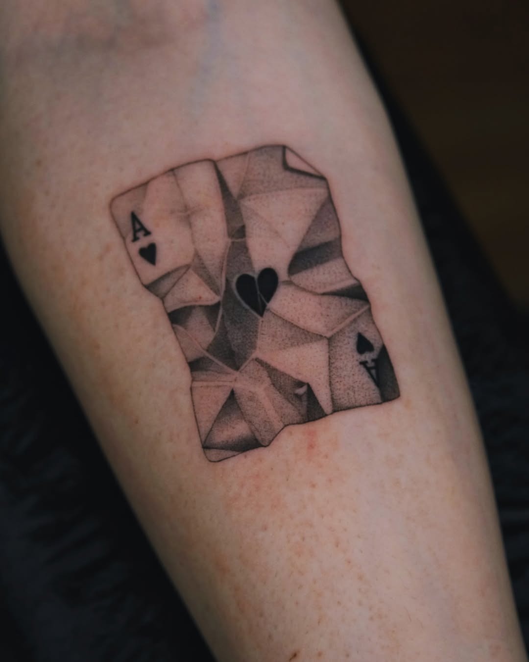 This tattoo features a detailed playing card design, skillfully crafted in dotwork style.