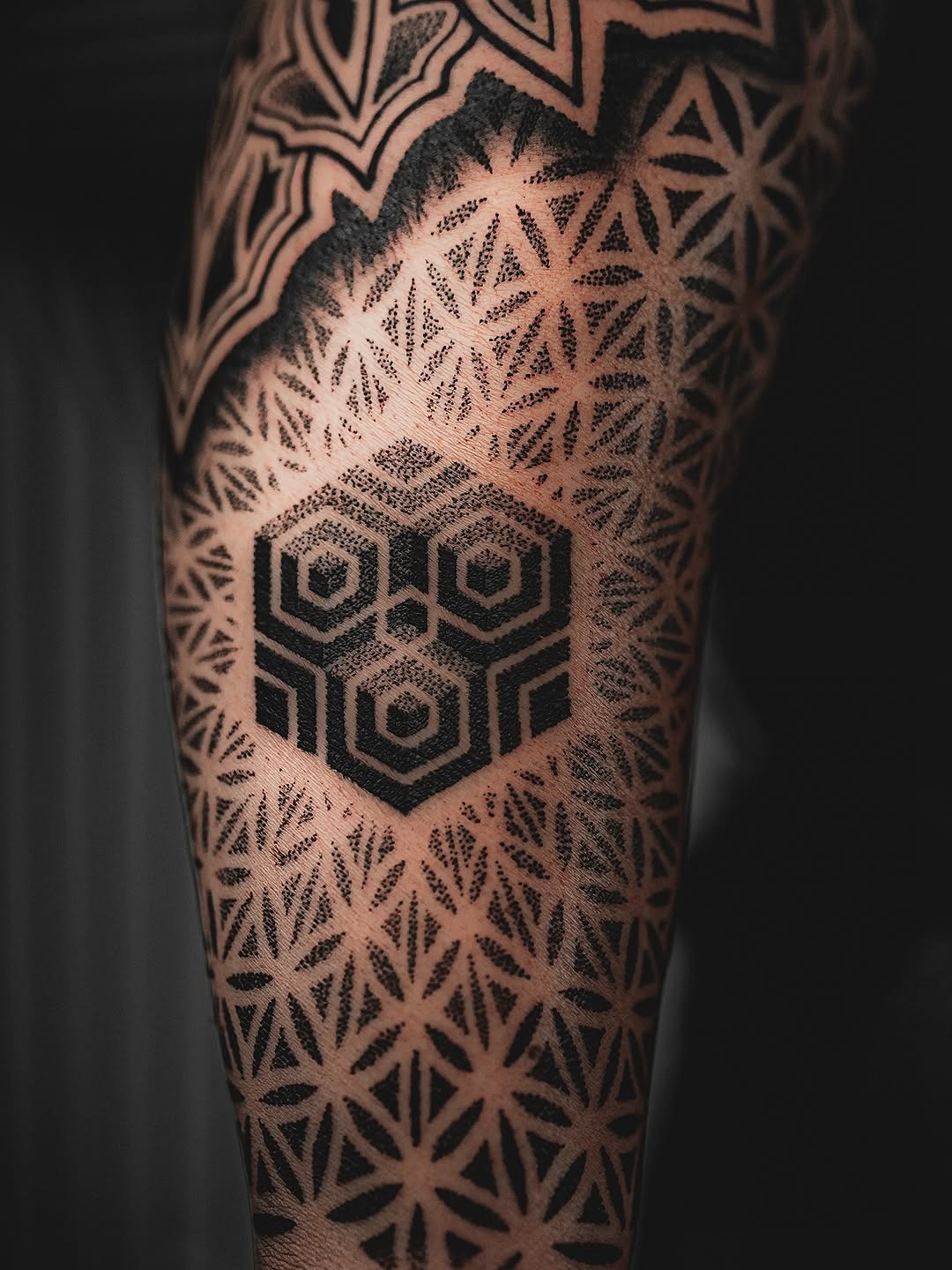 This tattoo showcases an intricate dotwork pattern, featuring geometric shapes and black ink.