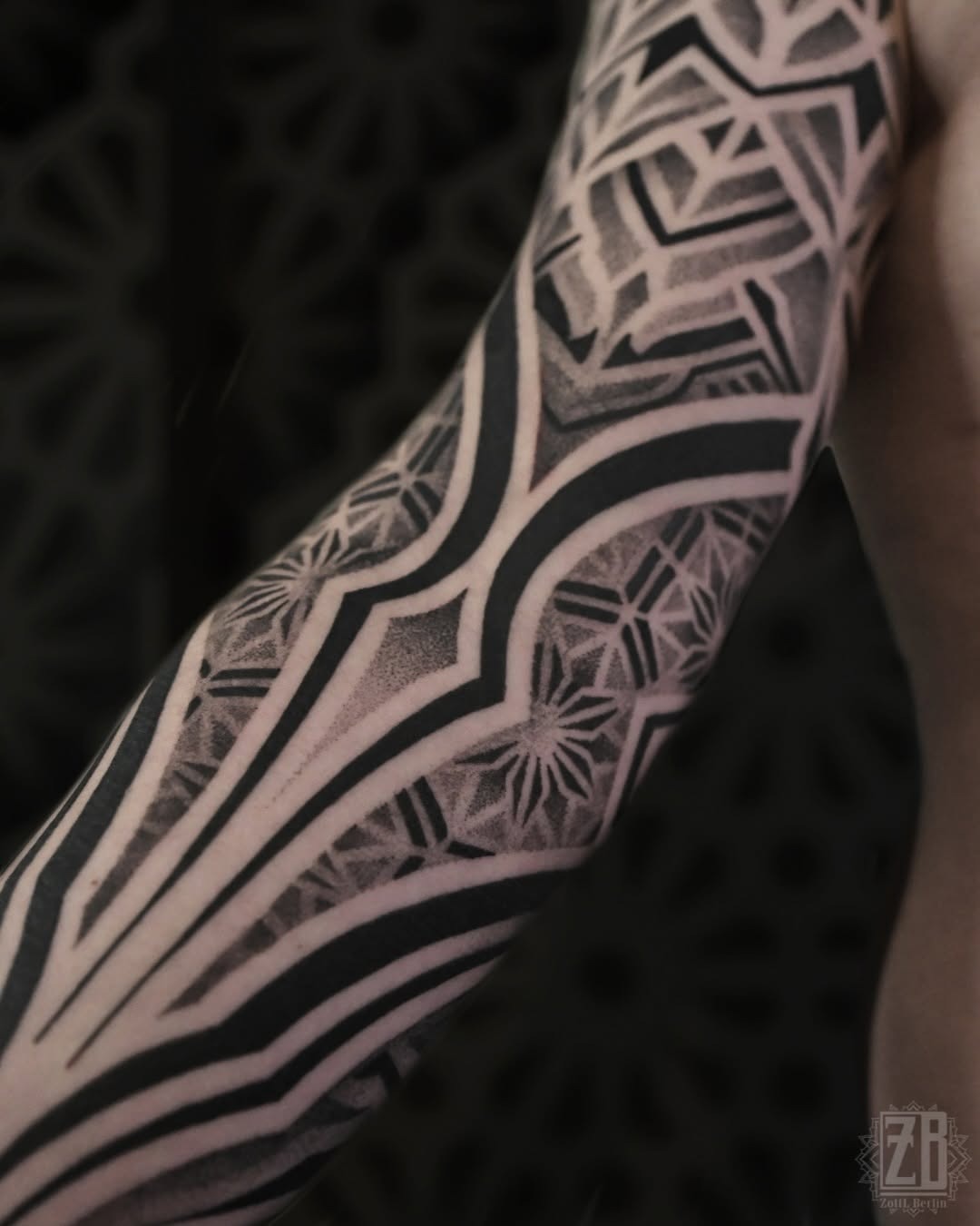 This tattoo showcases intricate geometric patterns through dotwork, creating a striking visual effect.