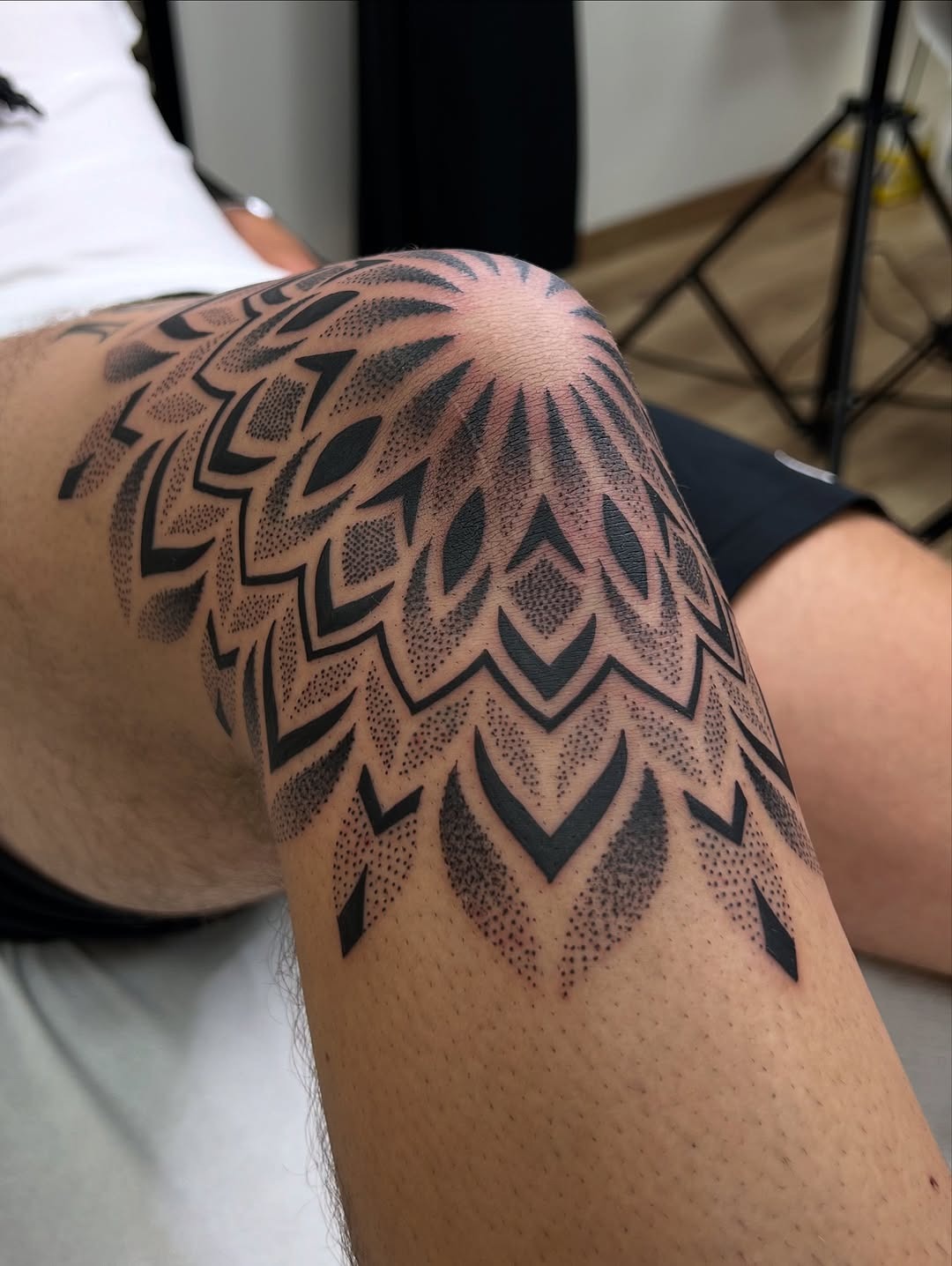 This stunning knee tattoo features a mandala design crafted entirely in dotwork style, showing intricate patterns that flow beautifully.