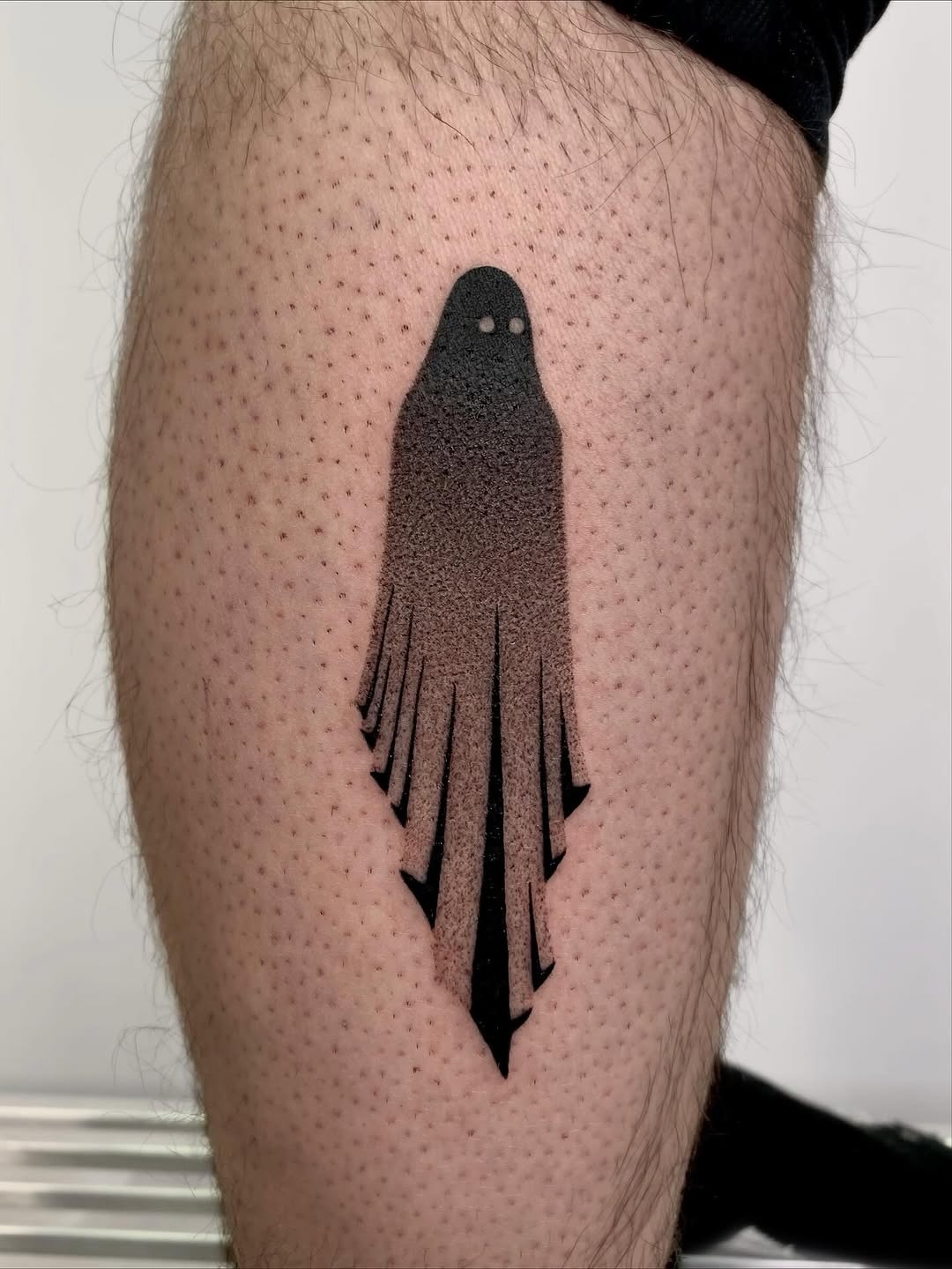 This dotwork tattoo depicts a striking ghost figure, blending bold black lines and intricate dot shading.