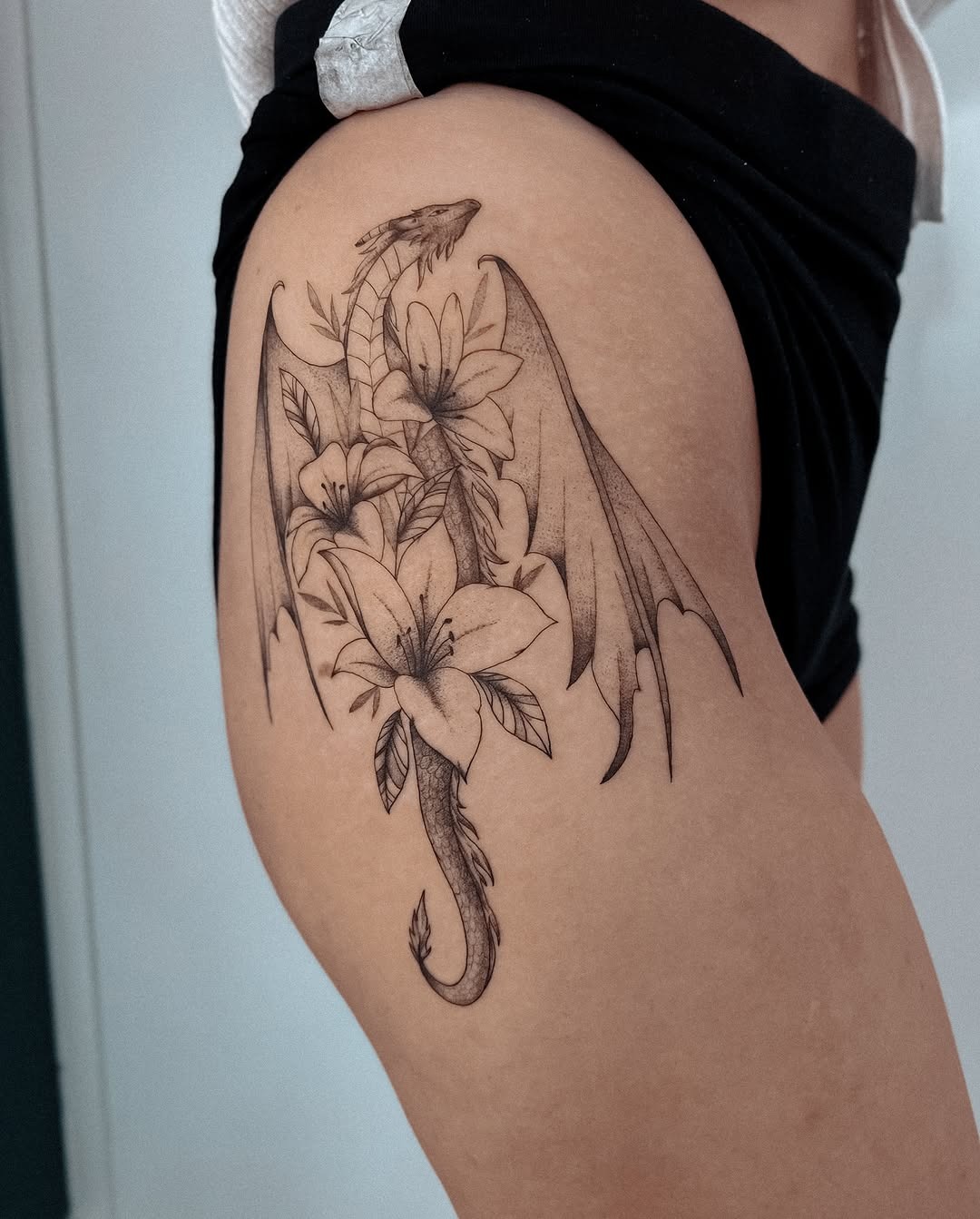 Elegant dragon intertwining flowers on thigh Tattoo Design