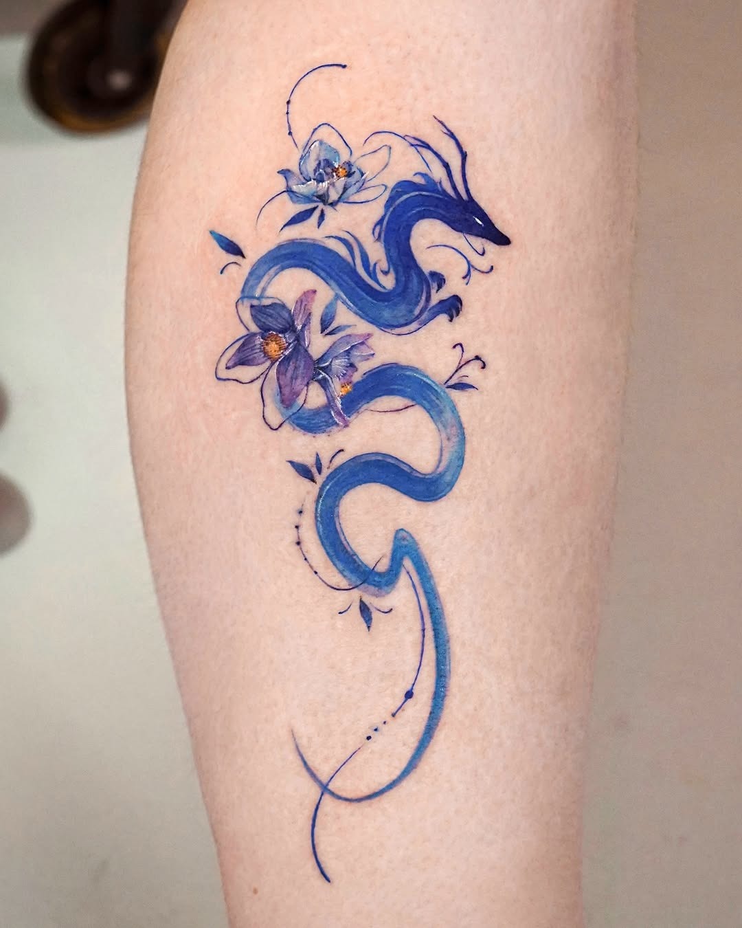 Intricate blue dragon design with floral accents Tattoo Design