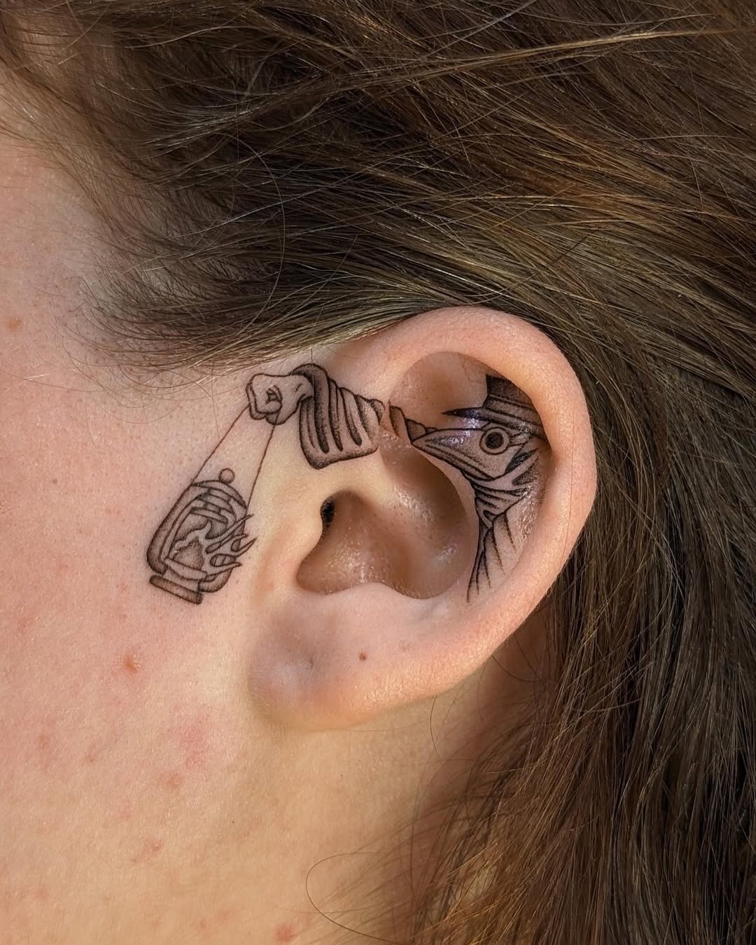 A whimsical fish-catching tattoo inside an ear Tattoo Design