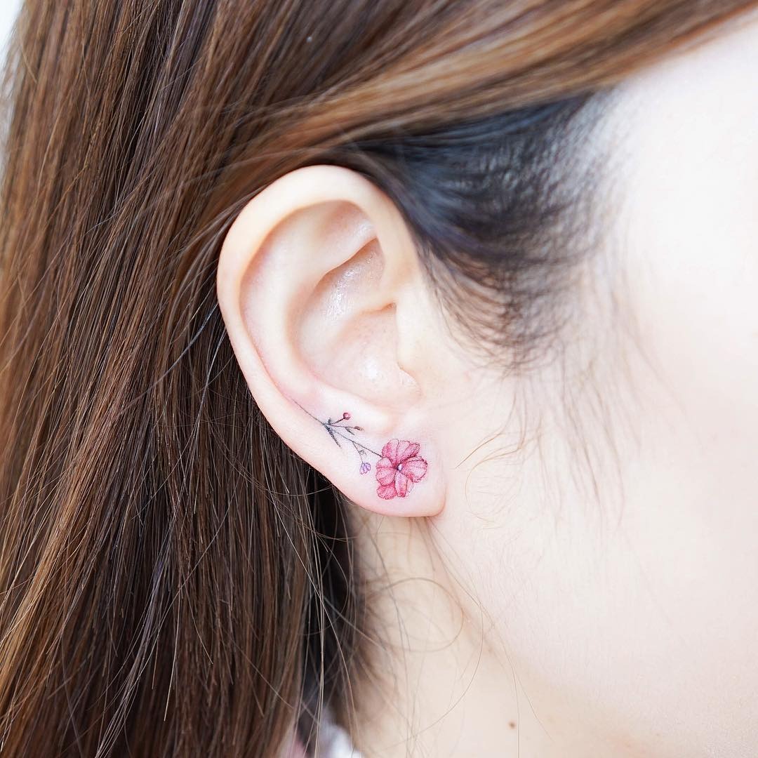 Delicate flower tattoo on ear adds charm Tattoo Design