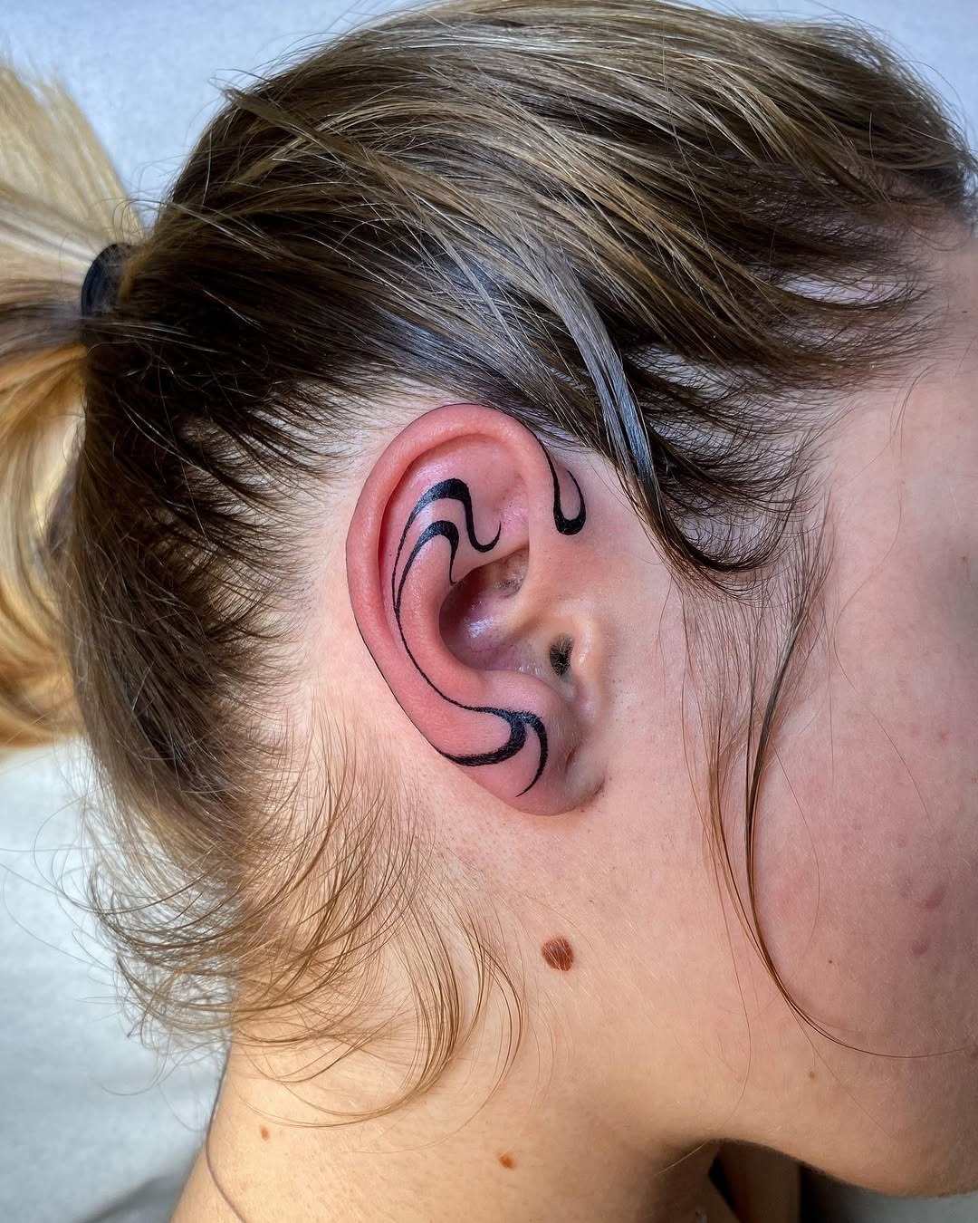 Elegant black line art tattoo on ear Tattoo Design