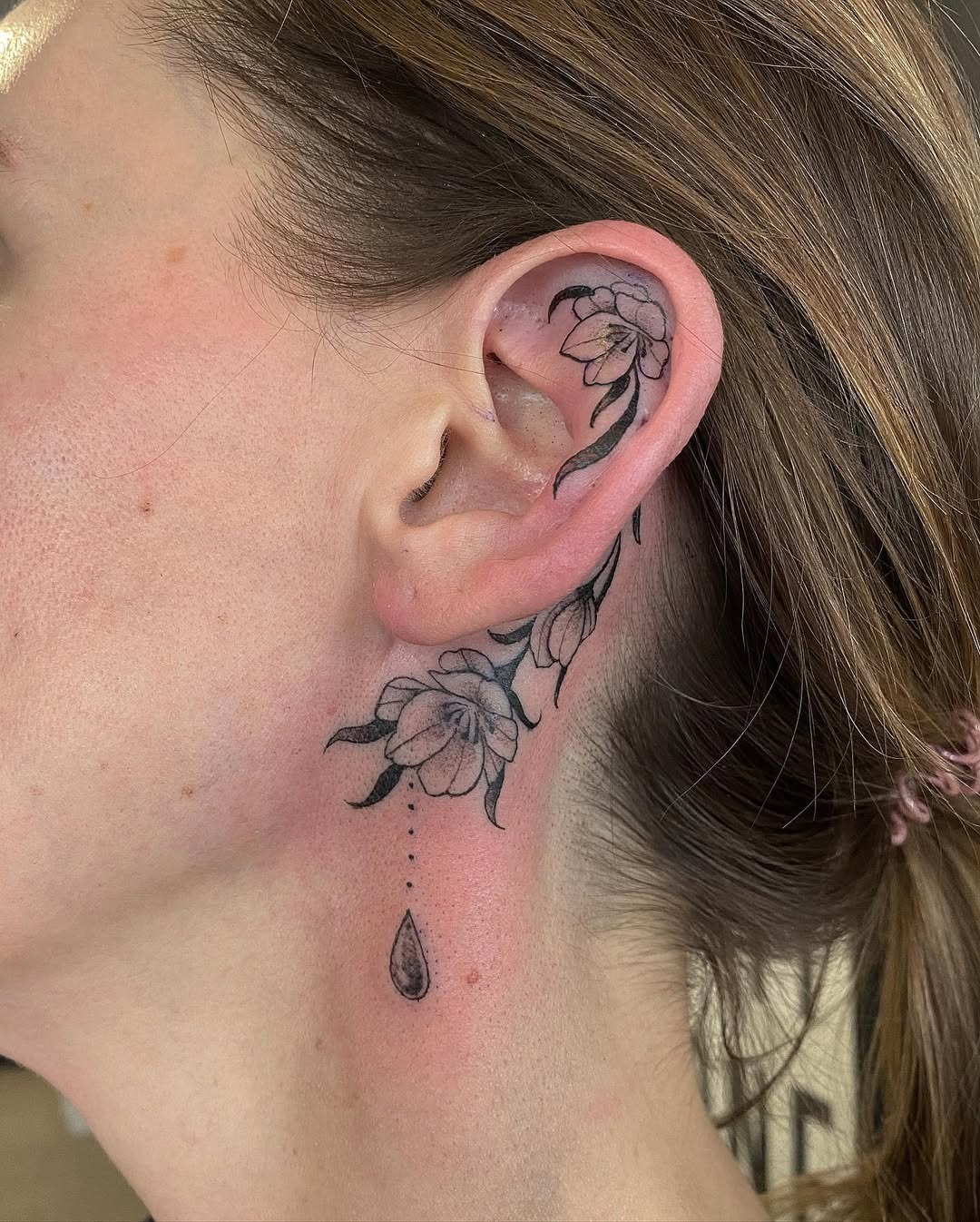 Elegant floral ear tattoo with droplet detail Tattoo Design
