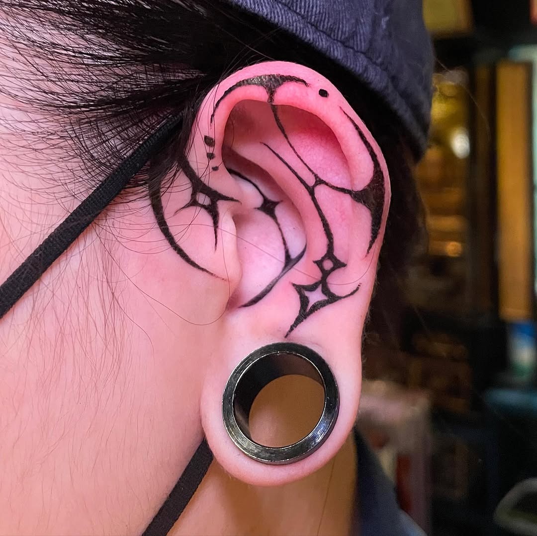 Intricate black outline ear tattoo with stars Tattoo Design