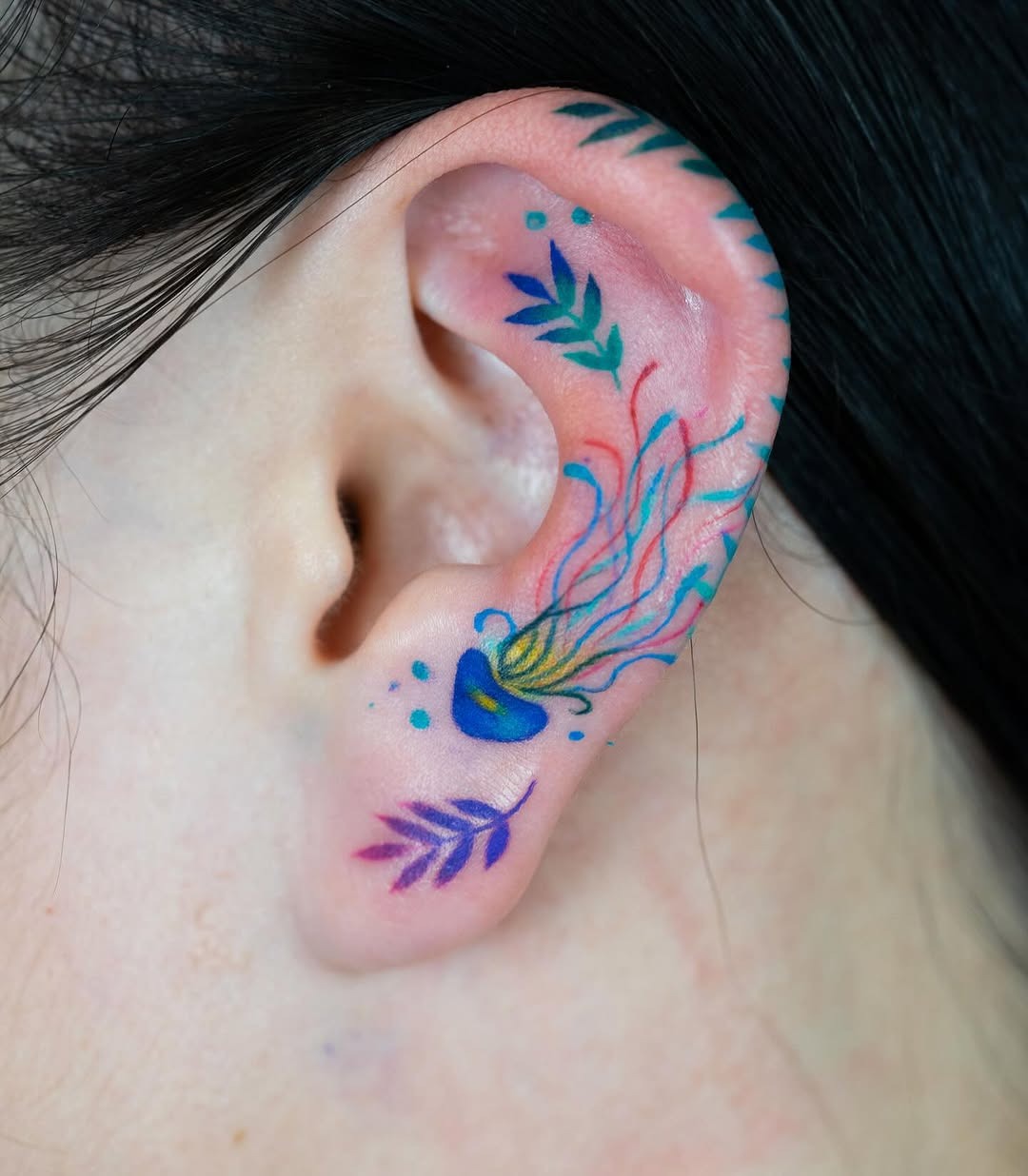 Vibrant jellyfish tattoo nestled in the ear Tattoo Design