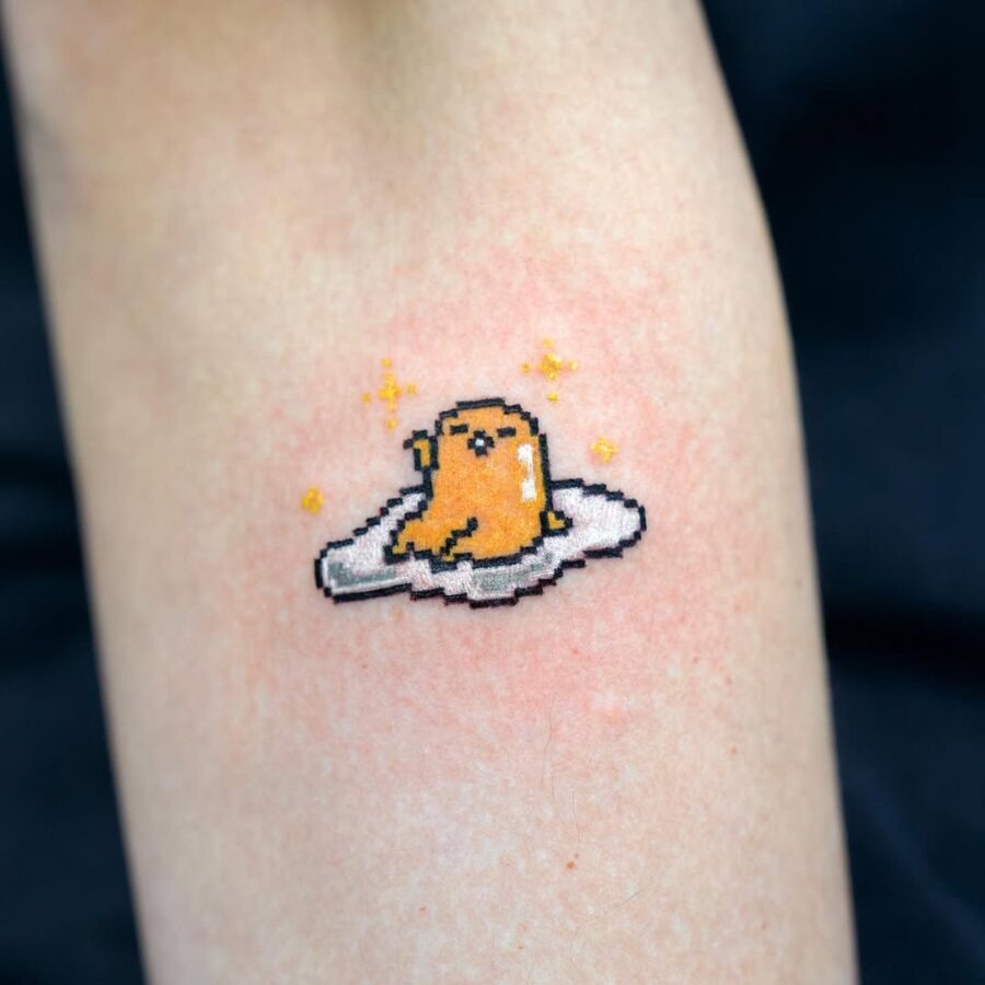 This adorable tattoo showcases a pixelated egg character resting on a cloud.
