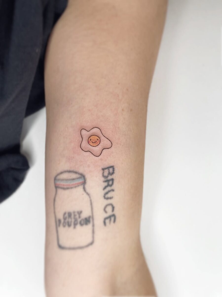 This playful egg tattoo features a cheerful smiling face, bringing a lighthearted vibe.