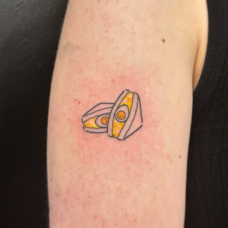 This fun egg tattoo features a quirky depiction of a cracked egg with yellow yolks.