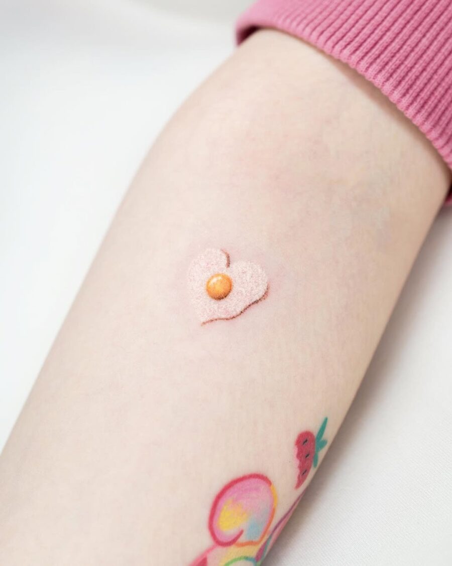 This adorable egg tattoo features a heart shape highlighted by a charming pearl in the center.