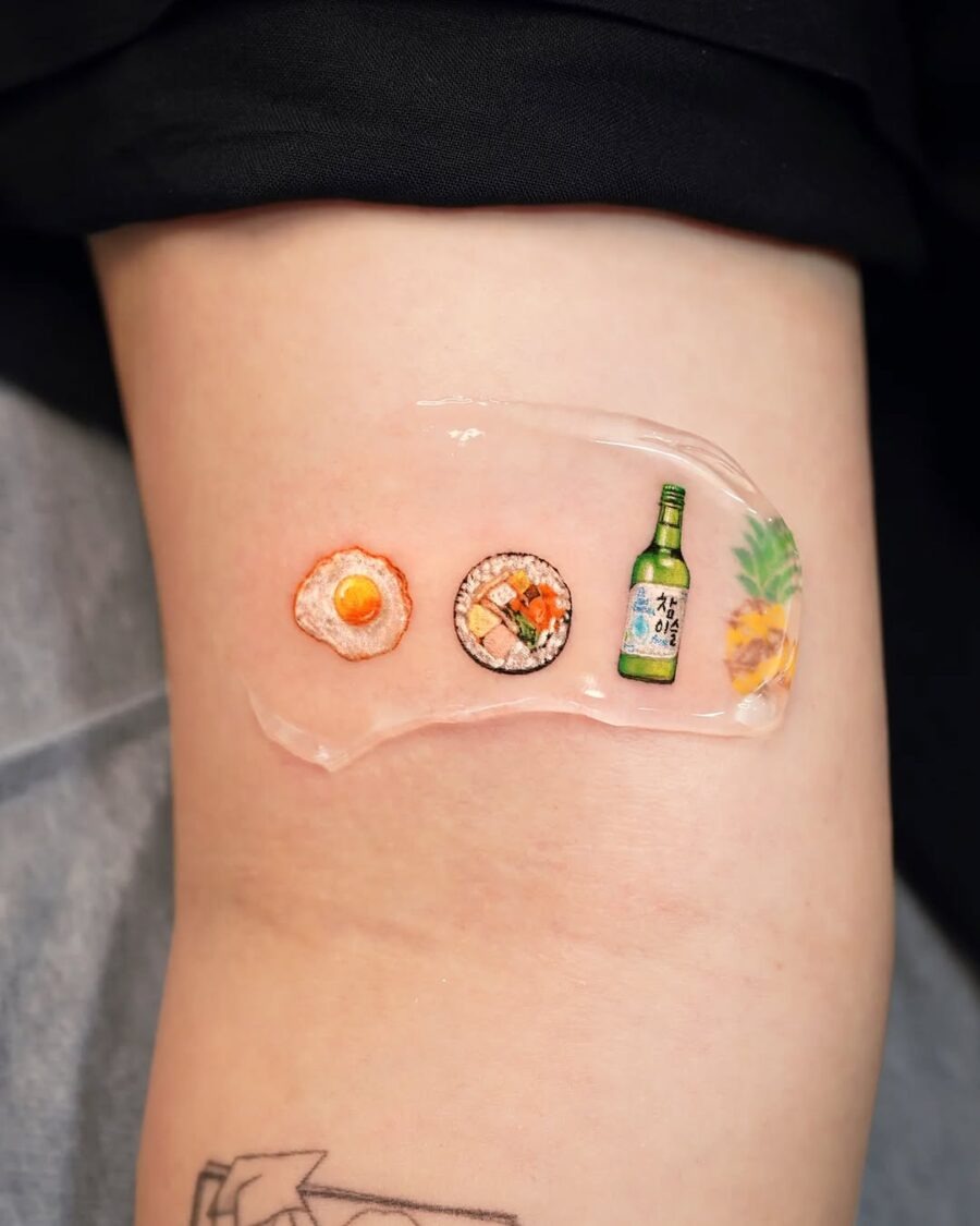 This tattoo features playful representations of food, including an egg, sushi, and a bottle, all beautifully inked on the skin.